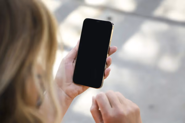 Foto einer Person, die ein iPhone mit ausgeschaltetem Bildschirm hält.