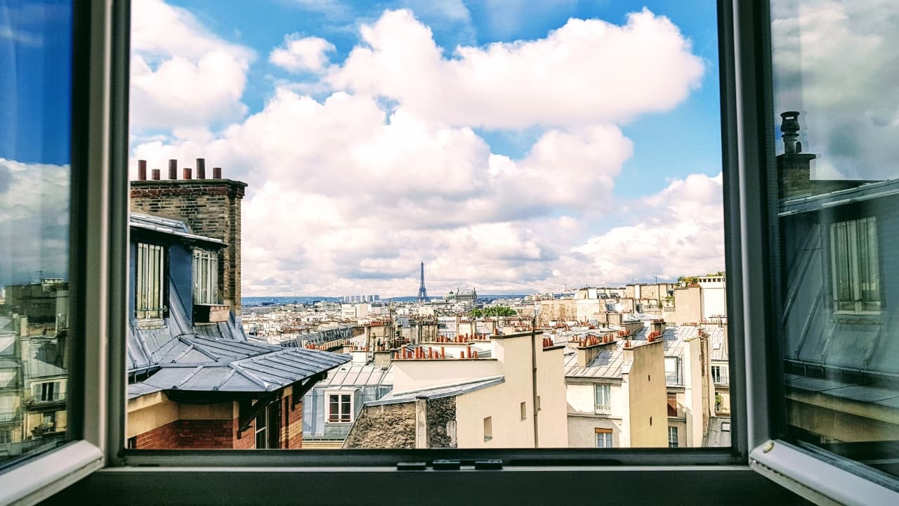 An out of a window view of Paris with the Eiffel tower in the far back.