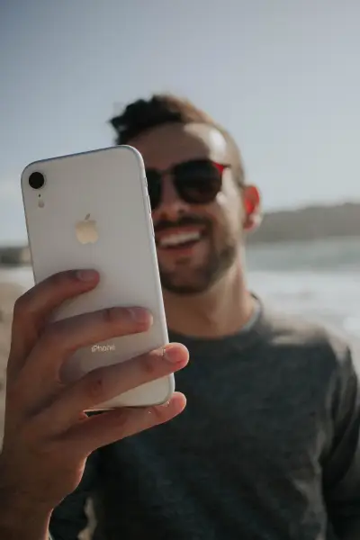 Photo of a man holding an iPhone and laughing.