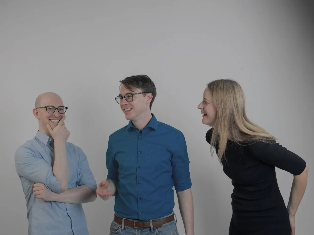 Gabriel Reimers, Julius Peinelt and Anna Neovesky laughing in front of a gray background